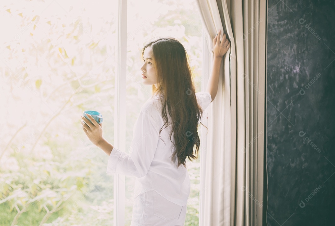 Asian woman drinking coffee in the morning sun