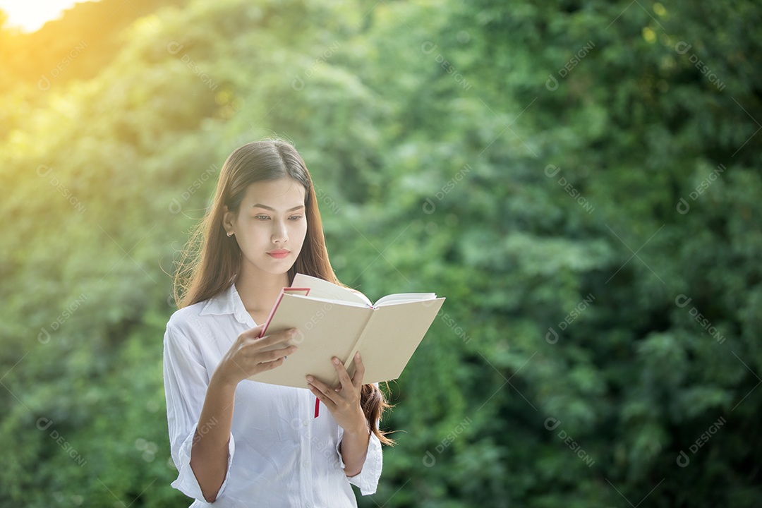 Livro de leitura favorito das mulher asiática ao ar livre em tempo incrível para relaxar