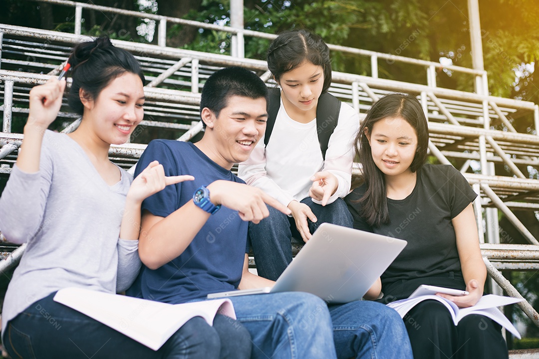 Grupo asiático de estudantes compartilhando ideias para trabalhar no gramado do campus