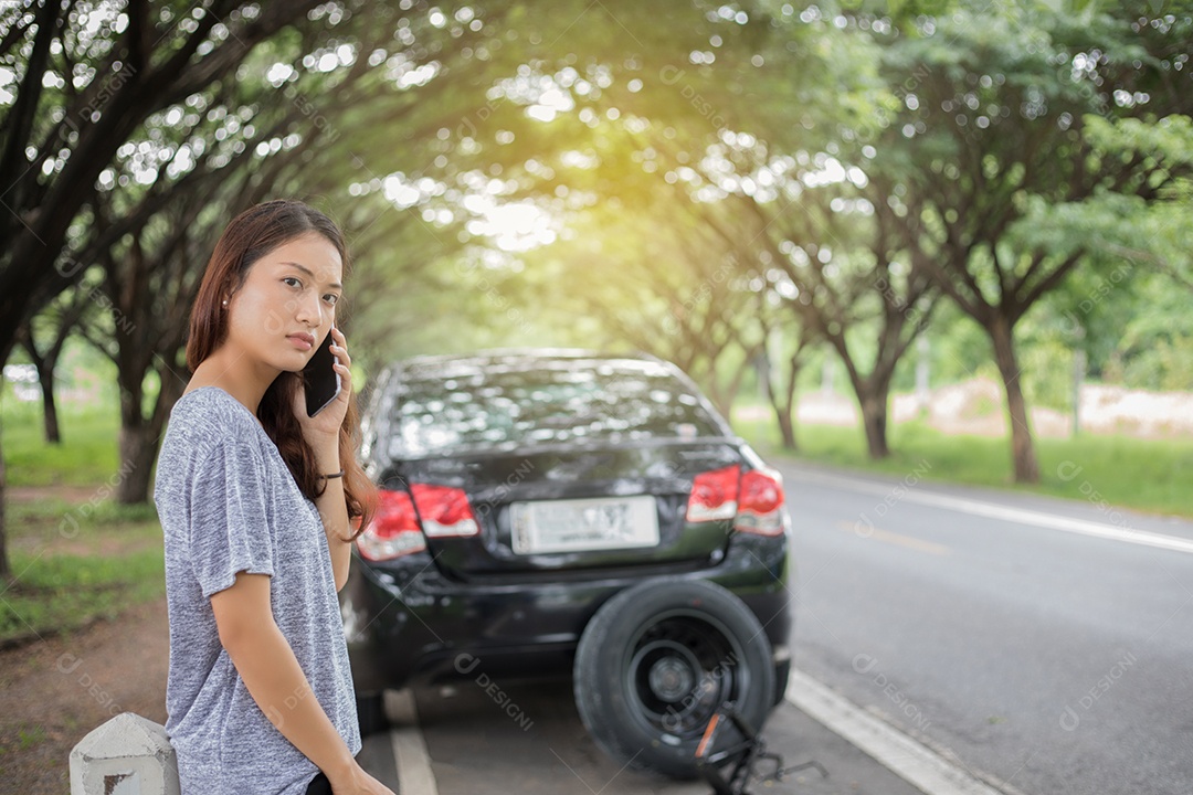 Mulher asiática usando telefone celular enquanto olha e homem estressado sentado após um colapso de carro na rua