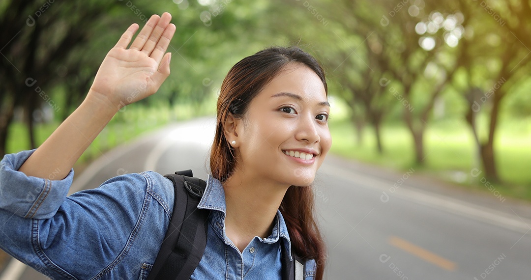 mulher asiática com mochila brilhante e mulher viajante da liberdade em pé com os braços levantados e desfrutando de uma bela natureza