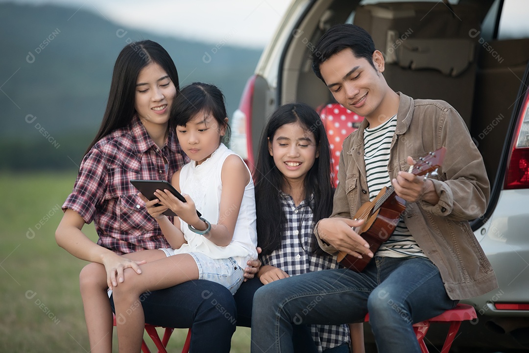 menina feliz tocando ukulele com família asiática sentado no carro para desfrutar de viagem e férias de verão