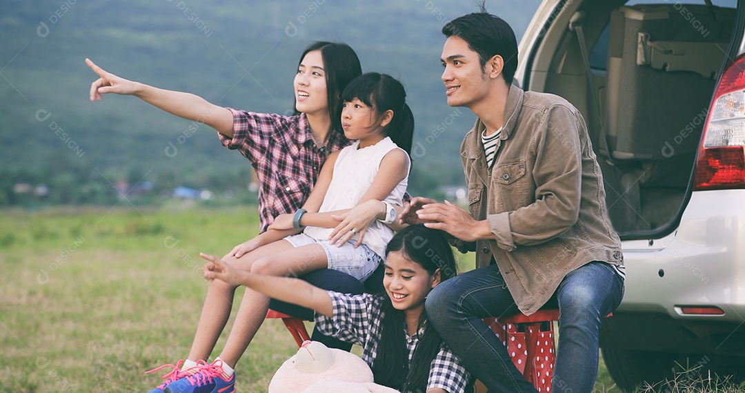 Menina feliz e com família asiática sentada no carro para curtir a viagem e as férias de verão na van campista