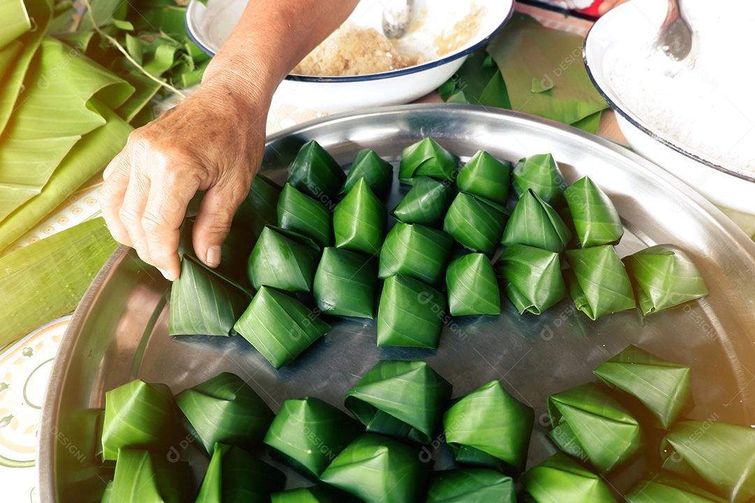 Fazendo doces folclóricos tailandeses embrulhados em folhas de bananeira devido ao festival de ano novo tailandês