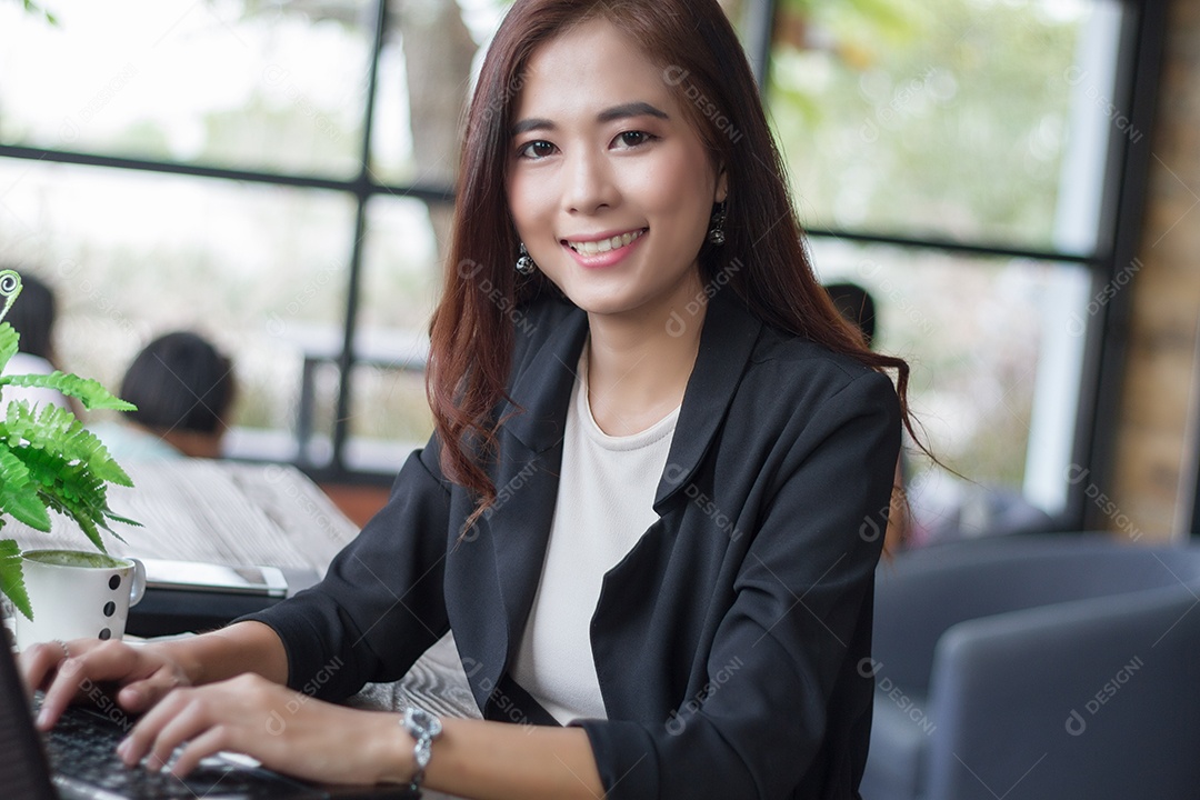 Mulher de negócios asiática usando notebook e mulheres de negócios sorrindo felizes por trabalhar