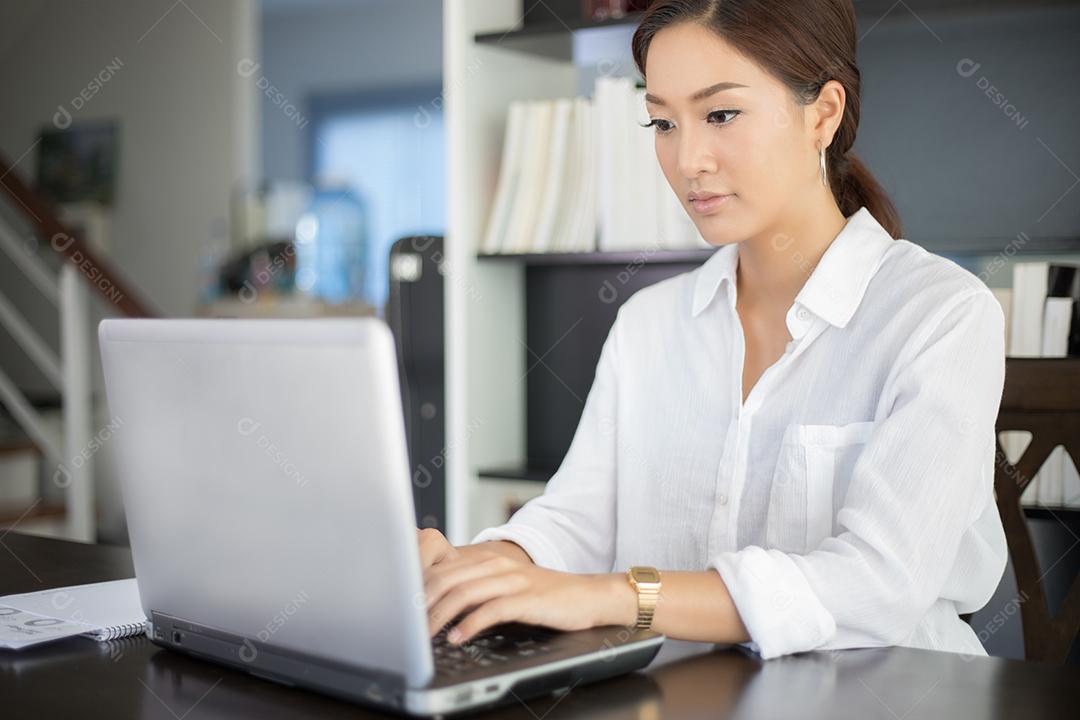 Mulher de negócios asiáticos usando notebook e sorrindo felizes por trabalhar