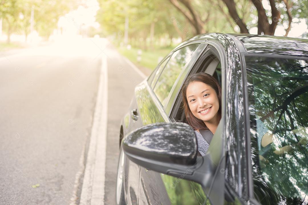 Linda mulher asiática sorrindo e se divertindo dirigindo um carro na estrada para viajar