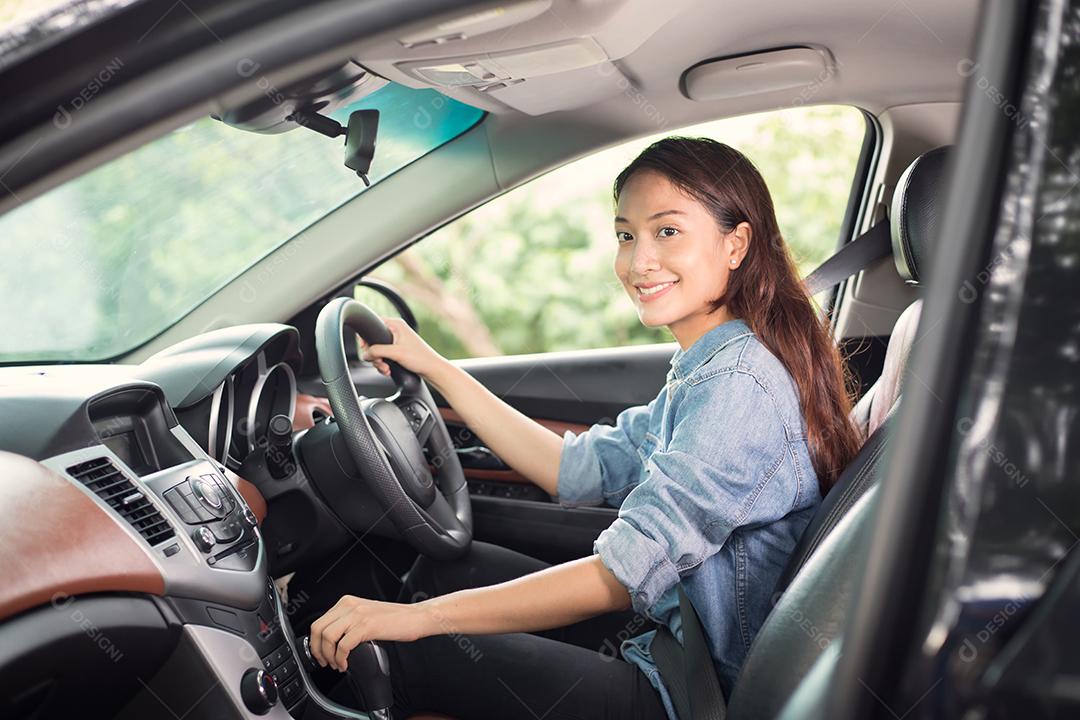 Linda mulher asiática sorrindo e gostando de dirigir um carro e a mão está prestes a entrar em marcha na estrada para viajar