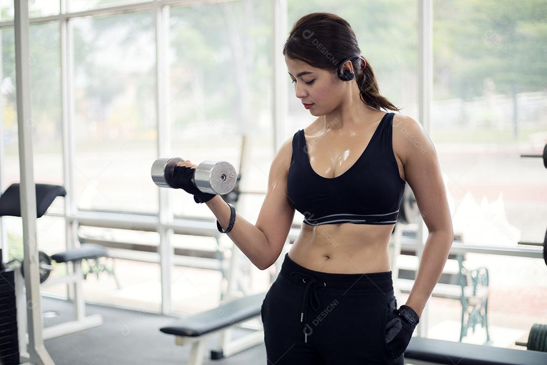 jovem fitness mulher asiática exercício com máquina Cable Crossover e levantamento de halteres e halteres no ginásio para construir músculos