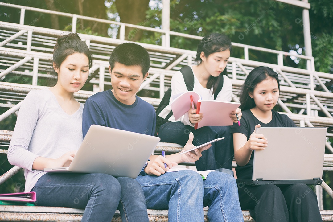 Grupo asiático de estudantes compartilhando ideias para trabalhar no gramado do campus