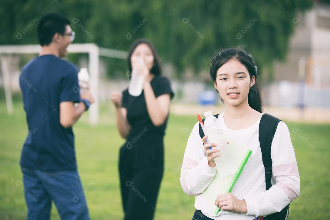 Asian group of students holding water bottle on campus lawn