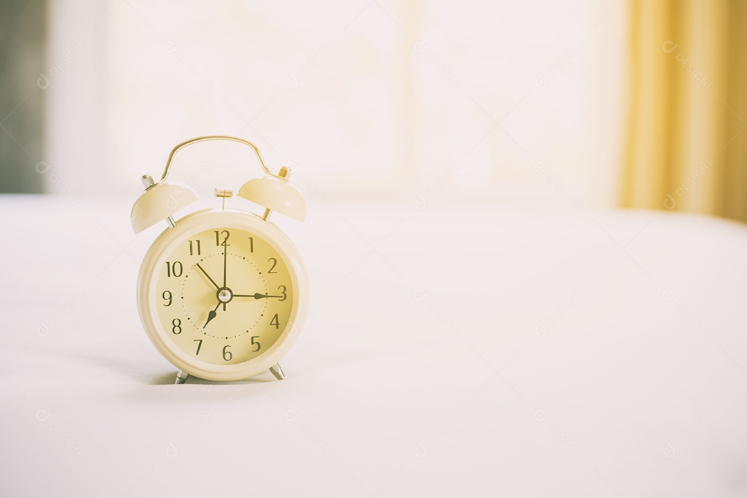 Despertador analógico na cama branca, hora da manhã com um sol brilhante