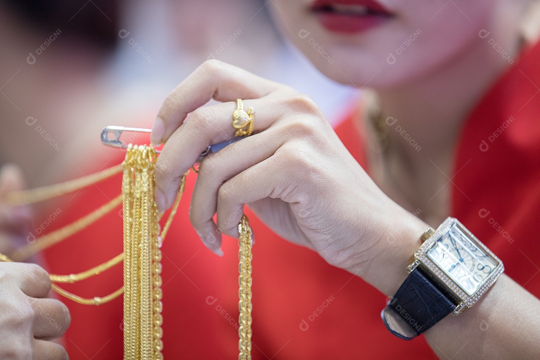 Jovem empresária segurando um colar de ouro para verificação de qualidade antes de comprar.