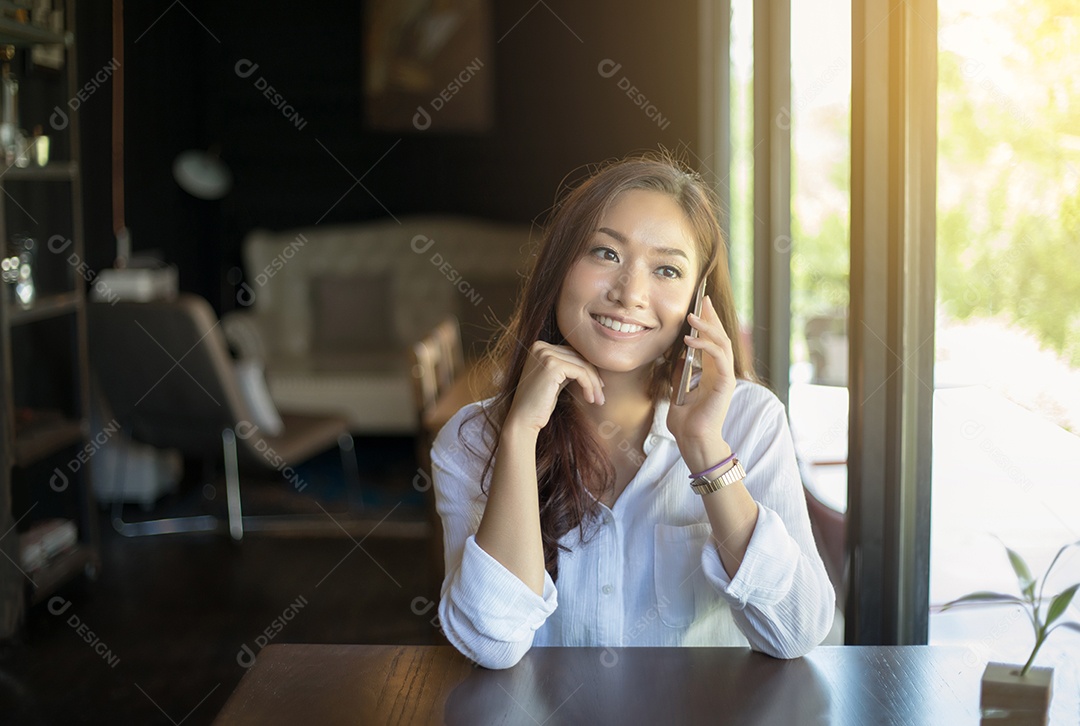 mulher asiática ligando com telefone celular enquanto está sentado sozinho no café durante o tempo livre