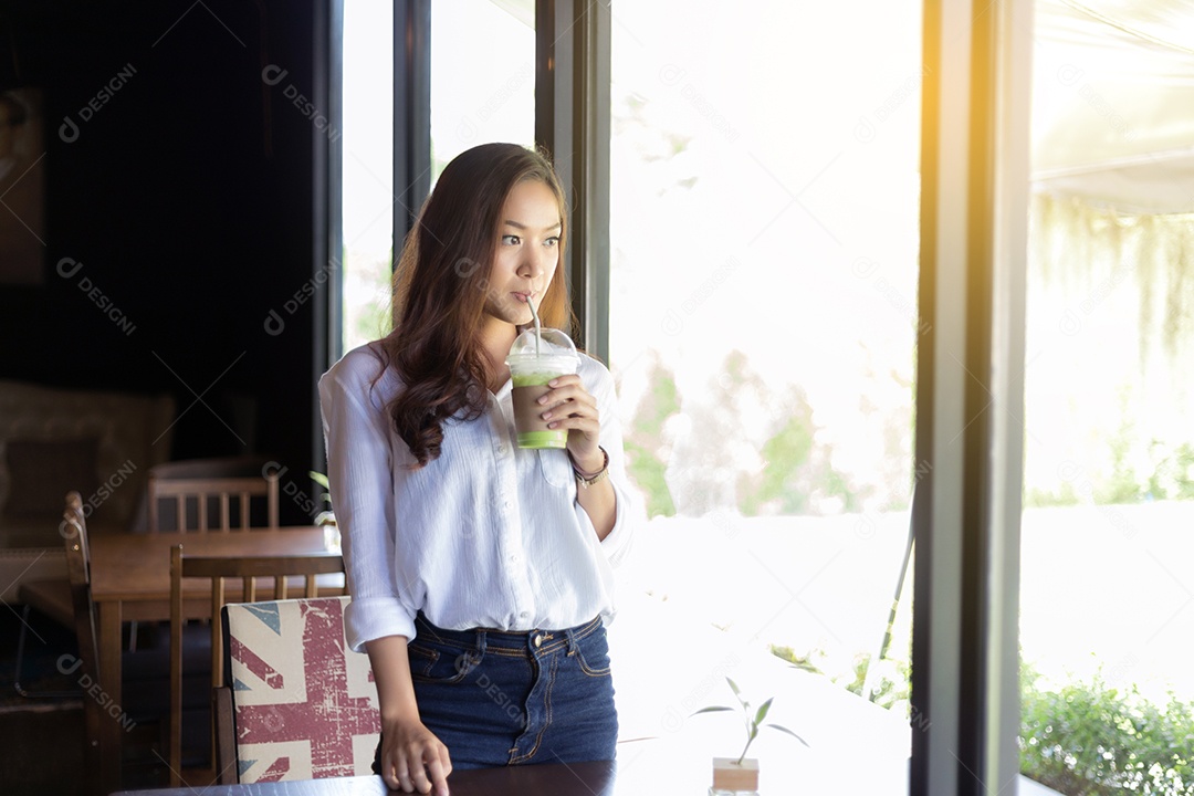 Mulher asiática estão tomando café e olhando para fora.