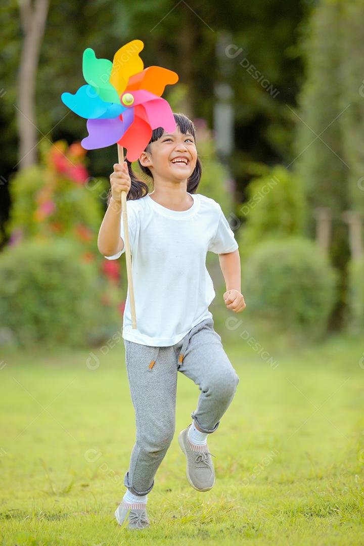 Menina bonitinha asiática brincando no moinho de brinquedo colorido