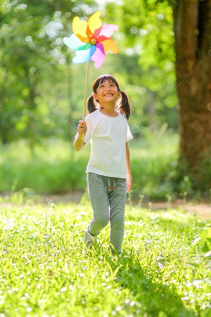 Menina bonitinha asiática brincando no moinho de brinquedo colorido