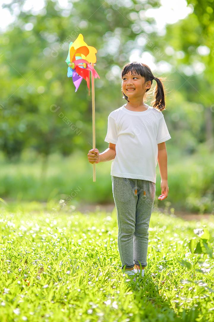 Menina bonitinha asiática brincando no moinho de brinquedo colorido