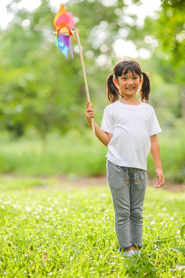 Menina bonitinha asiática brincando no moinho de brinquedo colorido