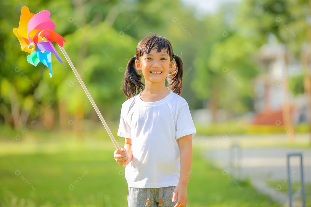 Menina bonitinha asiática brincando no moinho de brinquedo colorido