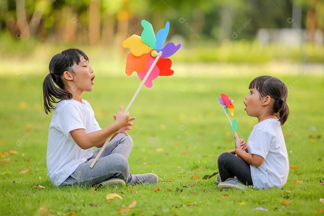 Two Asian cute girls playing in colorful toy windmill