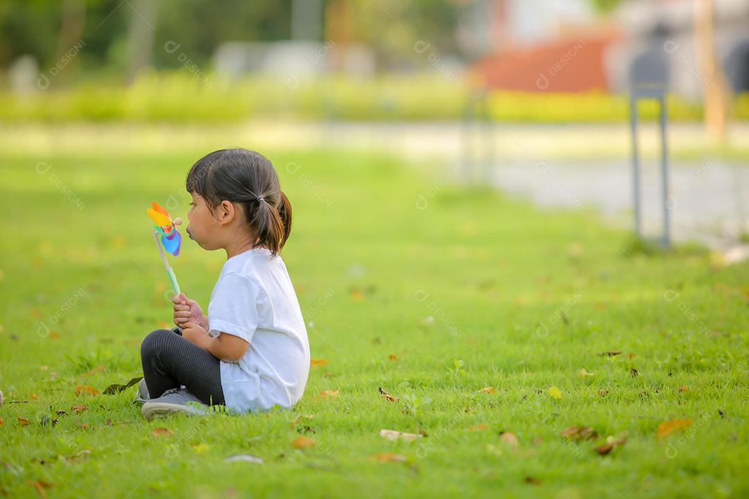 Menina bonitinha asiática brincando no moinho de brinquedo colorido