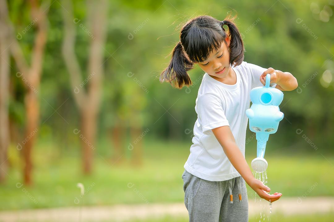 Menina bonitinha asiática regando as plantas que foram plantadas