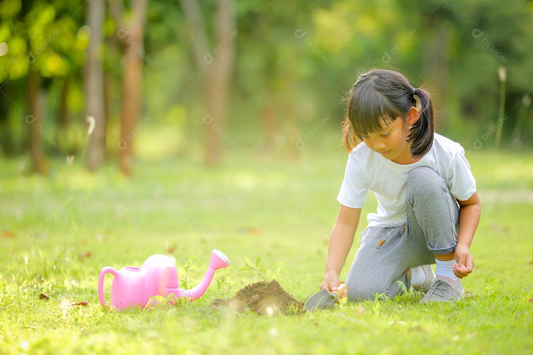 Menina bonitinha asiática regando as plantas que foram plantadas
