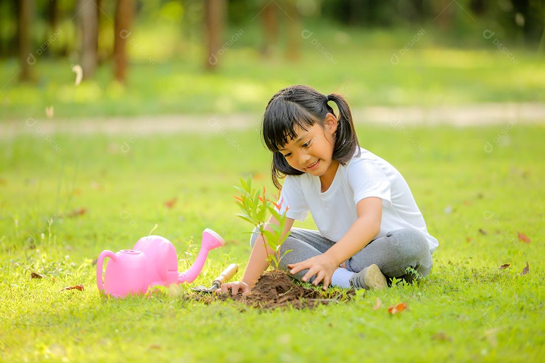 Menina bonitinha asiática regando as plantas que foram plantadas