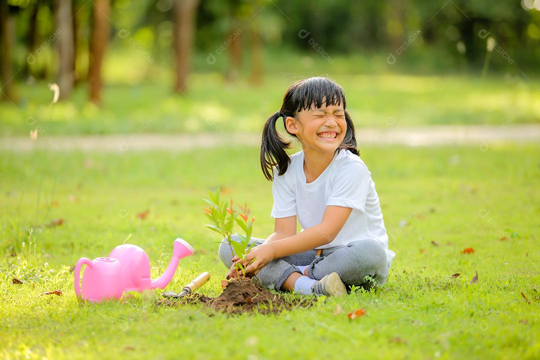 Menina bonitinha asiática regando as plantas que foram plantadas