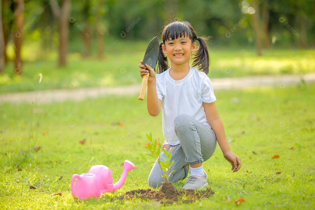 Menina bonitinha asiática regando as plantas que foram plantadas