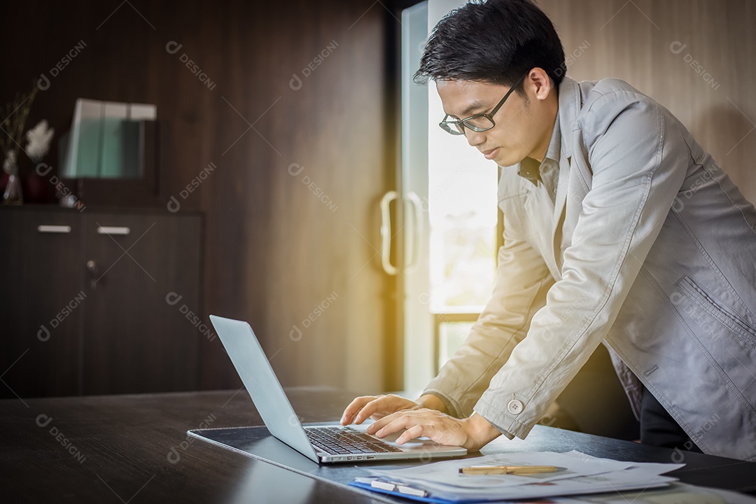 Empresário asiático usando notebook e documentos na mesa para trabalhar