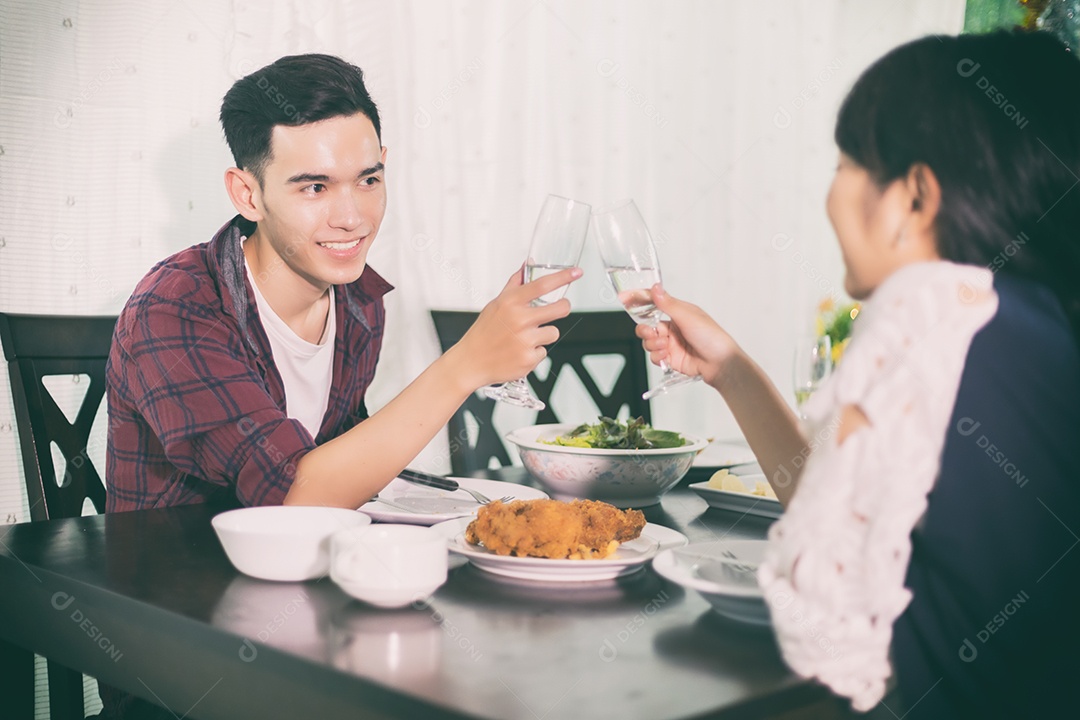 Casal jovem asiático desfrutando de um jantar romântico bebidas à noite enquanto está sentado à mesa de jantar na cozinha juntos