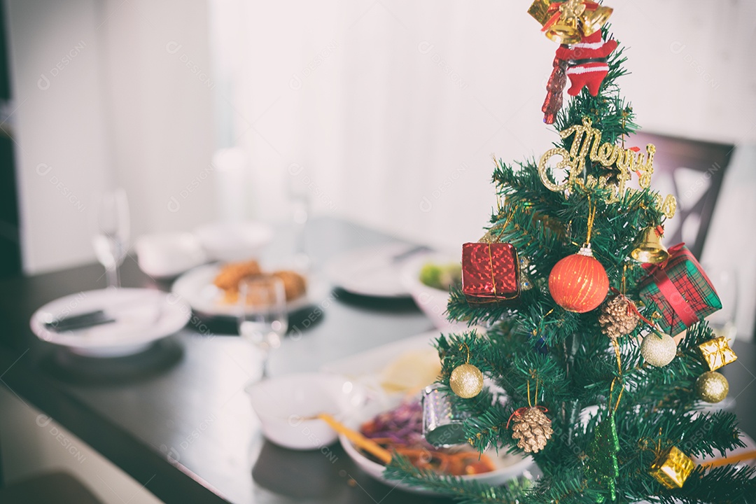 Árvore de natal na mesa para jantar com frango perto