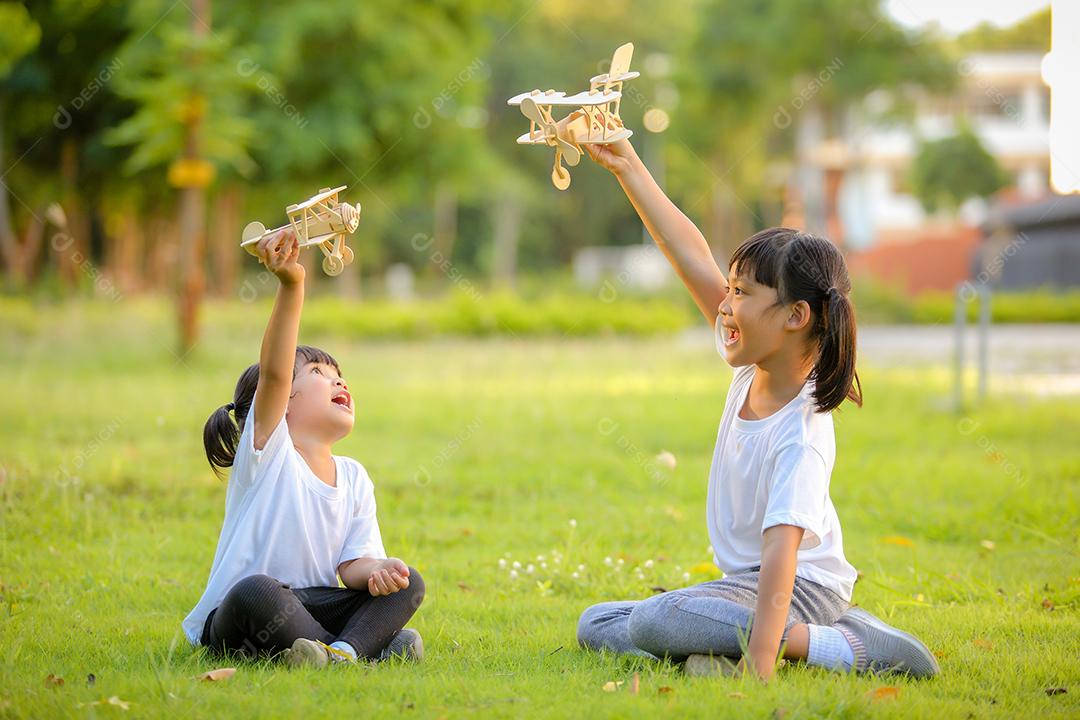 Meninas bonitinhas asiáticas brincando com avião de brinquedo na natureza no parque