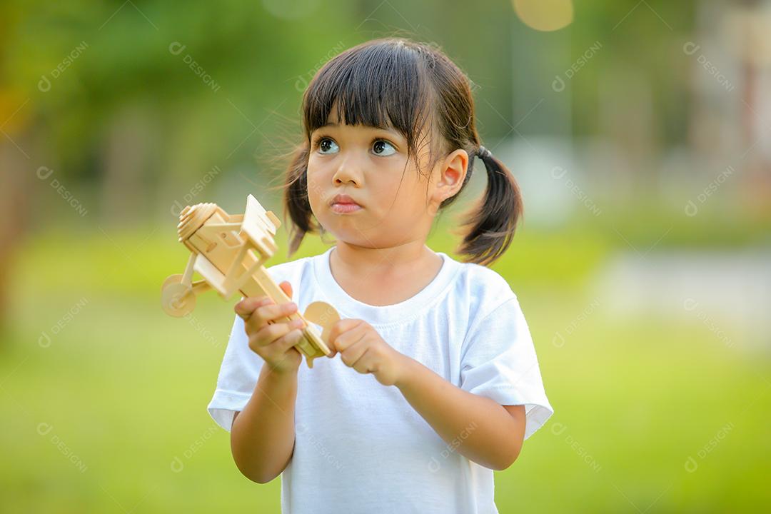 Menina bonitinha asiática jogando avião de brinquedo na natureza no parque