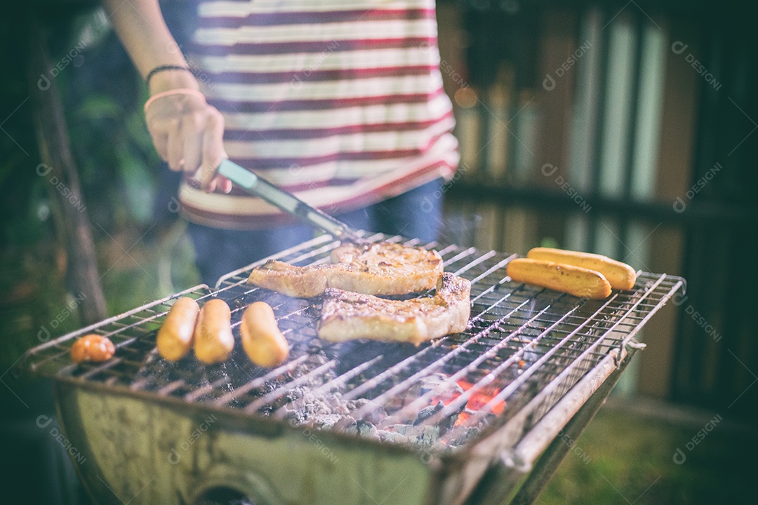 Grupo asiático de amigos fazendo churrasco e shashliks grelhados na festa grelhada no jardim ao ar livre