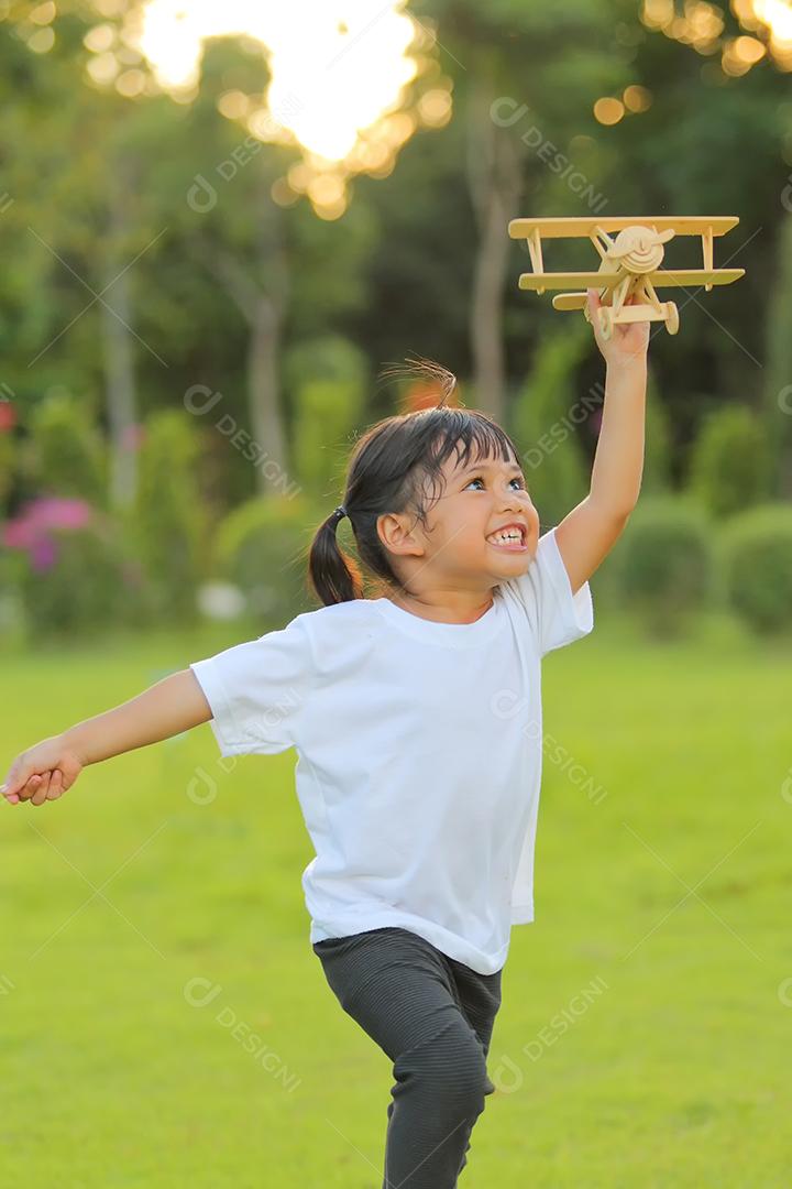 Menina bonitinha asiática jogando avião de brinquedo na natureza no parque