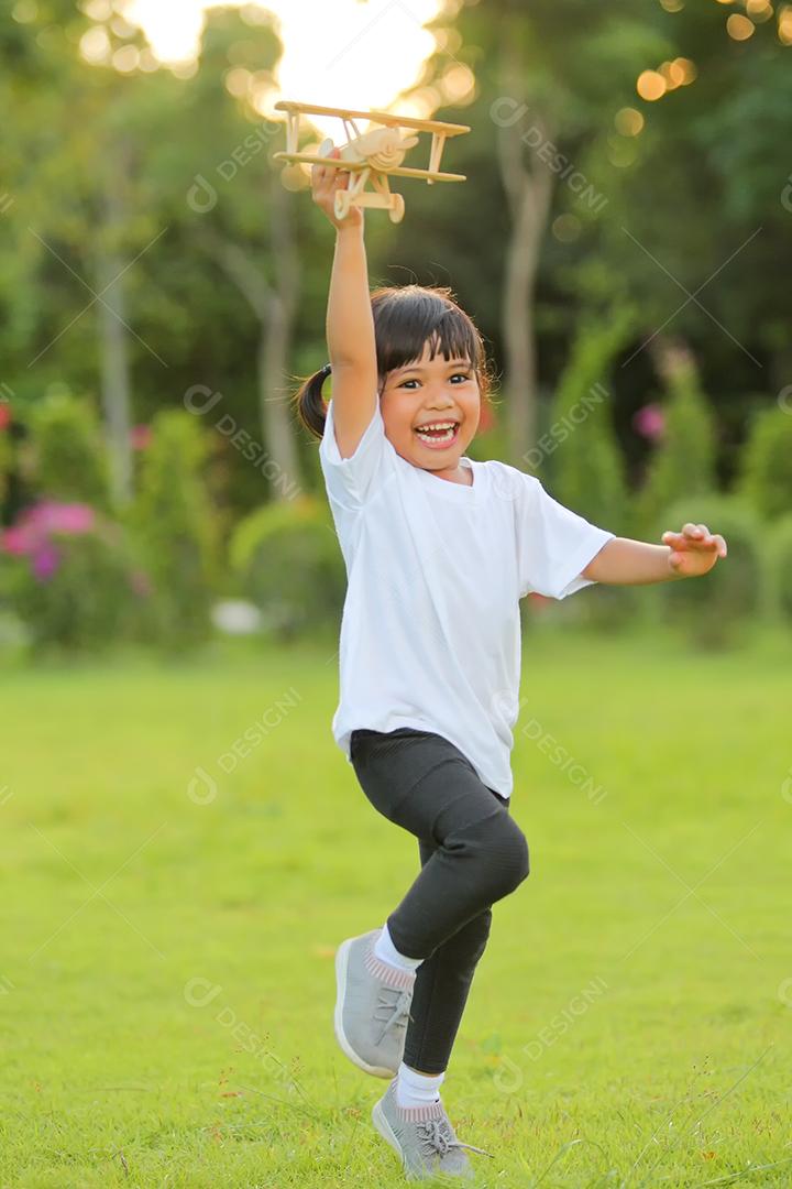 Menina bonitinha Ásia jogando avião de brinquedo na natureza no parque