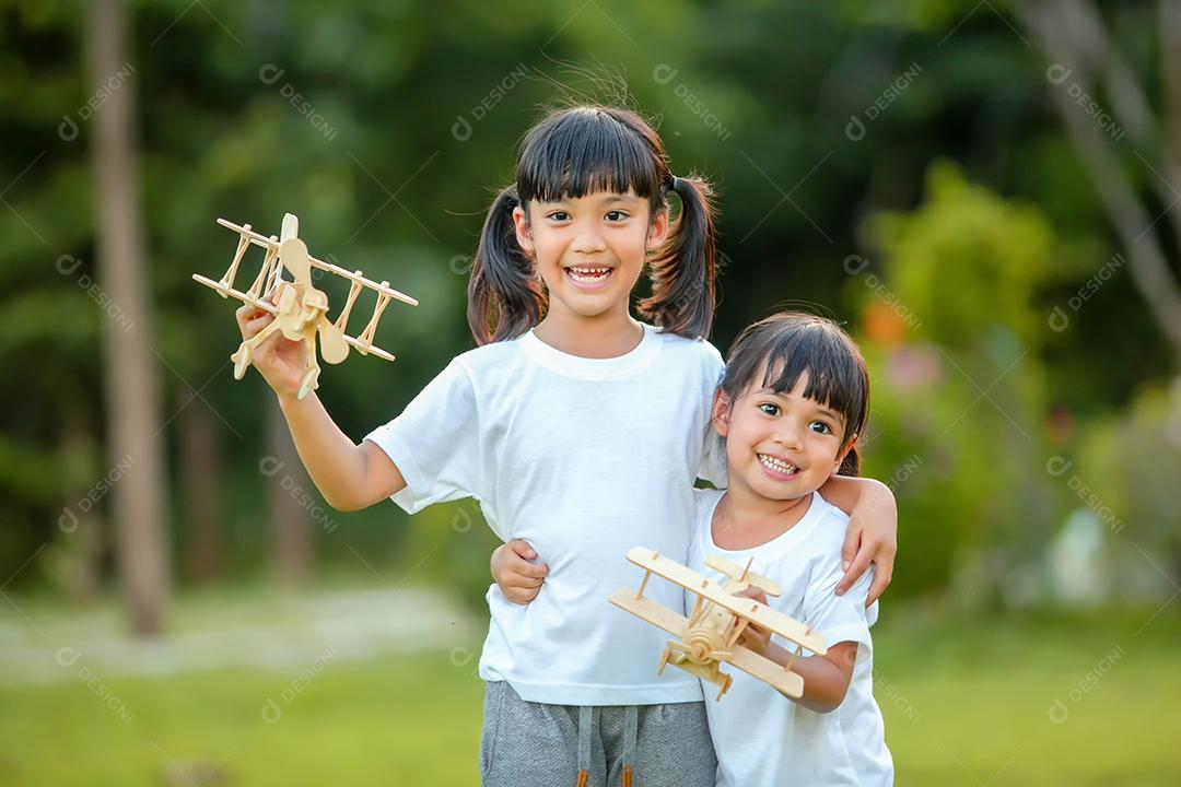 Meninas bonitinhas asiáticas brincando com avião de brinquedo na natureza no parque