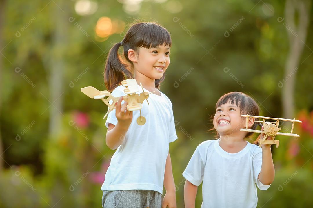 Meninas bonitinhas asiáticas brincando com avião de brinquedo na natureza no parque