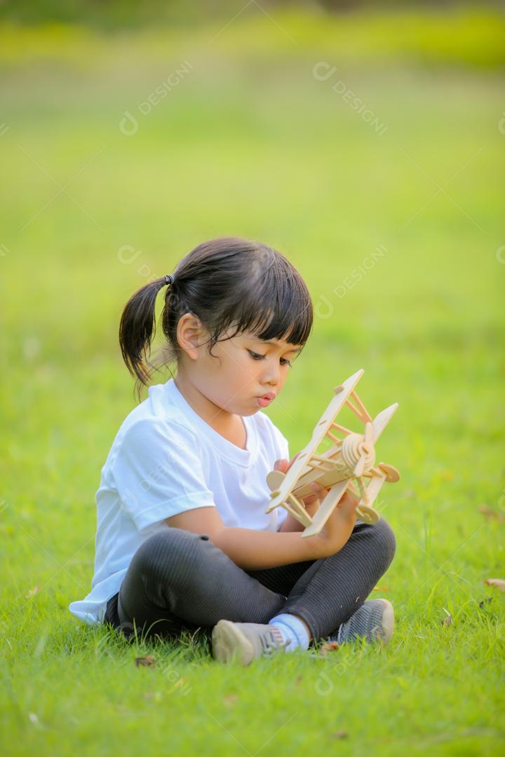Asian cute little girl playing toy plane in nature in park