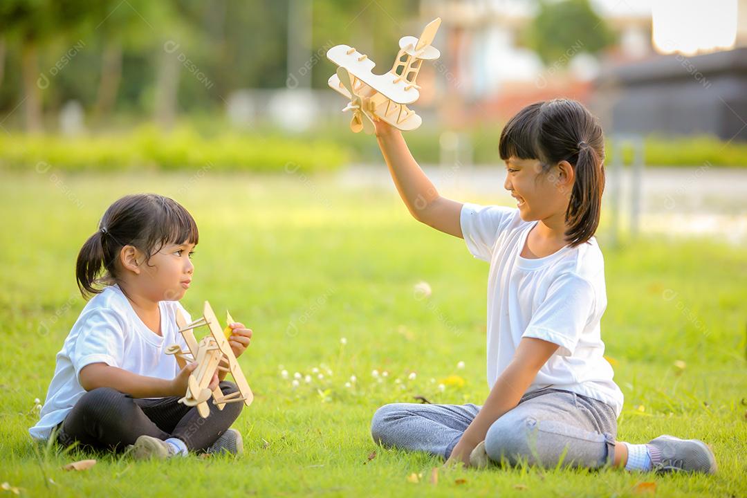 Meninas bonitinhas asiáticas brincando com avião de brinquedo na natureza no parque
