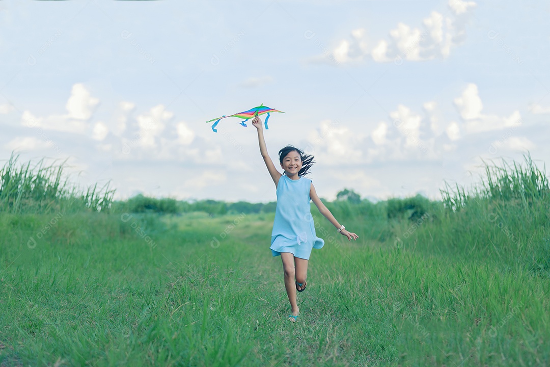 Menina asiática com uma pipa correndo e feliz no prado no verão na natureza