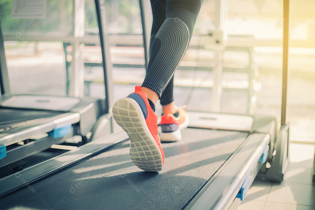 Desfoque de tênis de corrida na academia enquanto uma jovem caucasiana está correndo na esteira