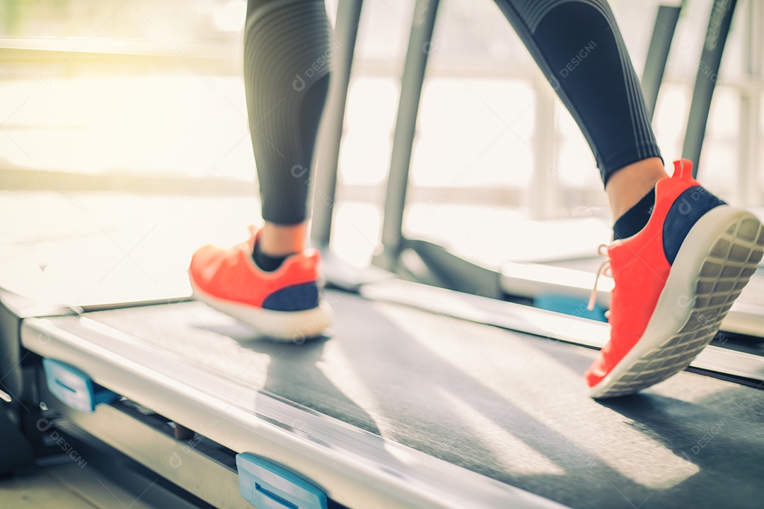 Desfoque de tênis de corrida na academia enquanto uma jovem caucasiana está correndo na esteira