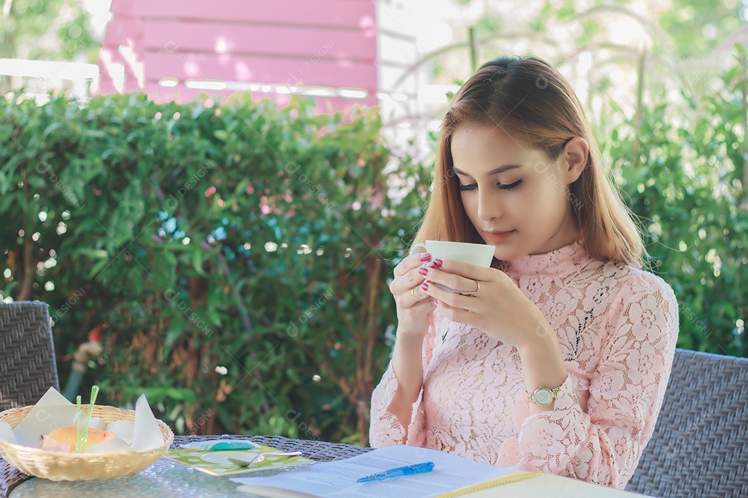 Mulher de negócios asiáticos está trabalhando e bebendo café ao ar livre