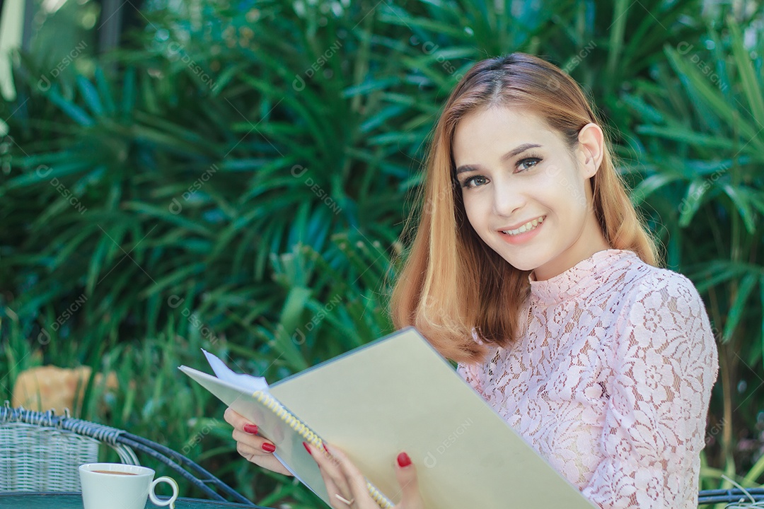 Mulher de negócio asiática sorrindo trabalhando e escrevendo um livro e verificando documentos ao ar livre, foco suave