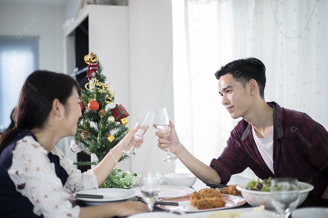 Casal jovem asiático desfrutando de um jantar romântico bebidas à noite enquanto está sentado à mesa de jantar na cozinha juntos,