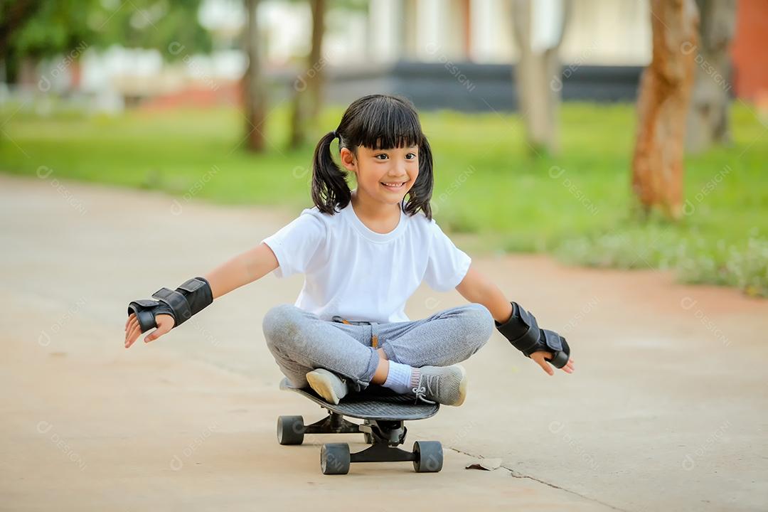 Menina bonitinha asiática andando de skate no parque de skate.